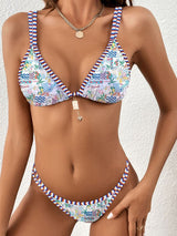Model posing in light tropical version of the triangle bikini set with statement pendant.